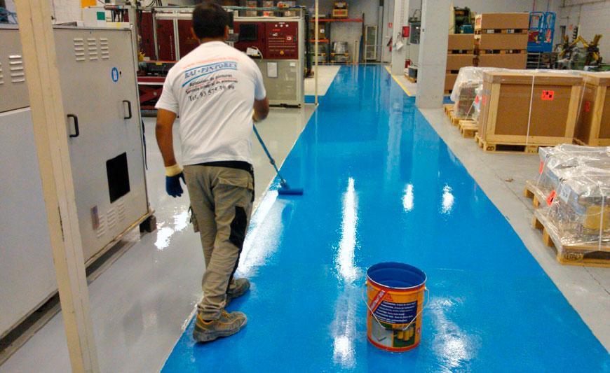 Aplicación de pintura epóxica azul en piso industrial